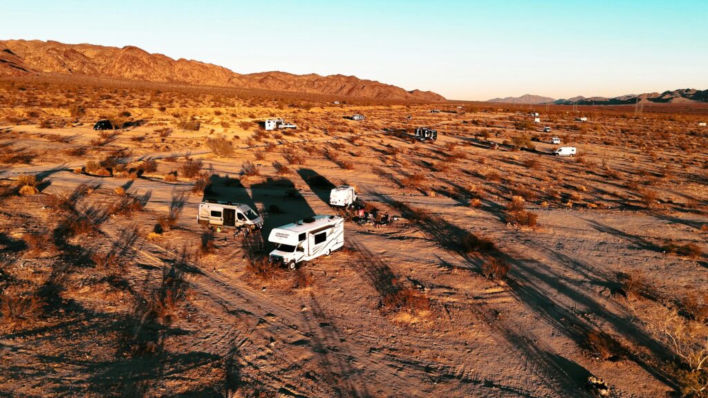 Aerial shot of RVs camped in a desert landscape at sunset, highlighting adventure travel.